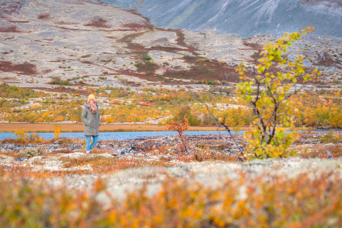 Frau steht in bunter Herbstlandschaft und denkt darüber nach, wie sie mehr Zeit für ihr Business freischaufeln kann,